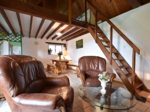 Lovely holiday home in Guilberville في Fourneaux: غرفة معيشة مع كرسيين جلديين وطاولة زجاجية