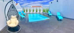 a patio with a pool and blue chairs and a swimming pool at Luxury Villa with Private Pool e Jacuzzi Year-Round a 25 min de Lisboa in Setúbal