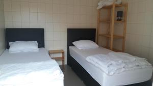 2 Betten in einem Zimmer mit weißen Decken darauf in der Unterkunft De Zandhoorn in De Panne