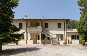 a large white house with a staircase in front of it at La Casa dei Pini in Gubbio