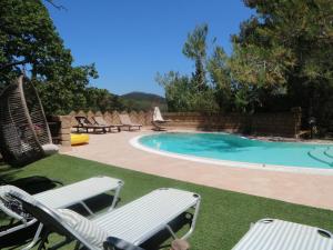 a swimming pool with two lawn chairs next to at Belvilla by OYO Villa Max in Suvereto