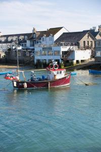 un bateau est amarré dans l'eau à côté des maisons dans l'établissement The Atlantic, à Hugh Town