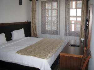 a bedroom with a bed and a desk and two windows at Simre Hotel in Amasya