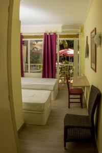 a hotel room with two beds and a chair at Hostal Alce in Playa de Palma
