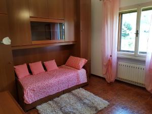 sypialnia z łóżkiem z różowymi poduszkami i oknem w obiekcie Appartamento Nerio w mieście Muggia
