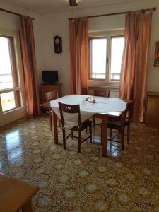 a dining room with a table and chairs and windows at Appartamento Nerio in Muggia