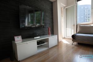 a living room with a tv on a brick wall at Warsaw Concierge Polin Apartment in Warsaw