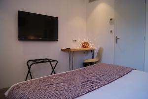 1 dormitorio con 1 cama y TV de pantalla plana en Contact Hôtel Le Minervois - Hôtel & Restaurant Au nord de Carcassonne en Caunes-Minervois