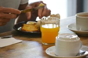 eine Person, die einen Teller mit Essen und ein Glas Orangensaft isst in der Unterkunft Moon Hill Hostel Sintra in Sintra