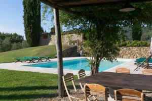 グレーヴェ・イン・キアンティにあるVilla Rosanoのスイミングプールの横のテーブルと椅子