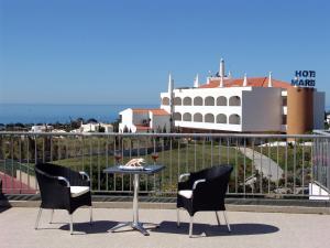 two chairs and a table on a balcony with a building at Apartamentos Maritur in Albufeira