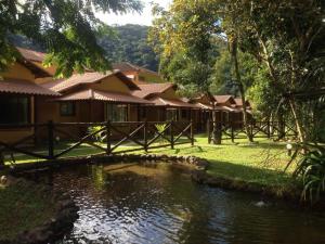 a house with a pond in front of it at Aldeia do Bambu Camping e Chalés in Quartéis