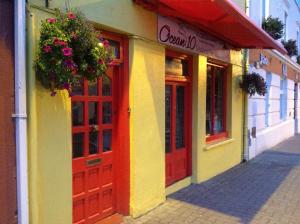 a store with red doors and flowers on a street at Sheehans On Main Street in Kenmare