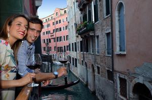 a man and a woman holding glasses of wine on a canal at Residenza Bistrot De Venise in Venice