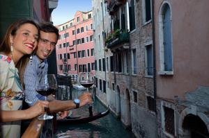 Ein Mann und eine Frau, die ein Glas Wein auf einem Kanal hält. in der Unterkunft Residenza Bistrot De Venise in Venedig