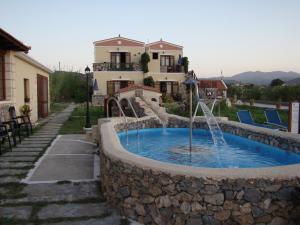a swimming pool with a fountain in a stone wall at Drapania Beach Marinakis in Kissamos