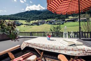 a table with an umbrella and a book on a balcony at Leni Mountain Appartements in Sölden
