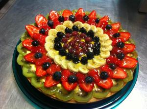a cake with fruit on a plate on a table at Hotel Novara in Verbania