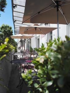 un patio al aire libre con mesas, sillas y sombrillas en Hotel Du Square en Riom