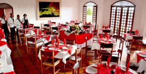 uma sala de jantar com mesas e cadeiras vermelhas e brancas em Hotel Serra do Ouro em Jacobina