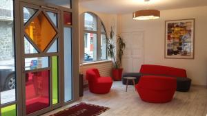 - un salon avec des chaises rouges et un canapé dans l'établissement Hôtel de Perros, The Originals Boutique, à Perros-Guirec