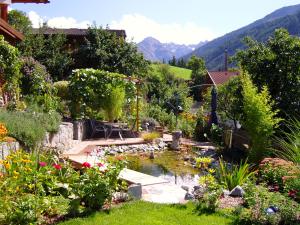 un jardín con un estanque con flores y una montaña en Apart Annelies, en Kauns