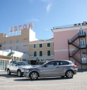 due auto parcheggiate in un parcheggio di fronte a un edificio di Hotel O Novo Principe ad Almeirim