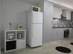 a kitchen with a white refrigerator with a microwave on top at Casa Pirosa in Aveiro