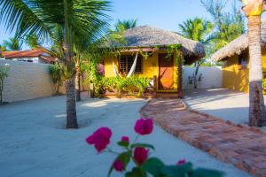 a yellow house with palm trees and pink flowers at Pousada Vento do Kite in Barra Grande