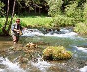 Ein Mann steht in einem Bach mit einem Fisch in der Unterkunft Gasthof Schwarzer Bär in Kastl