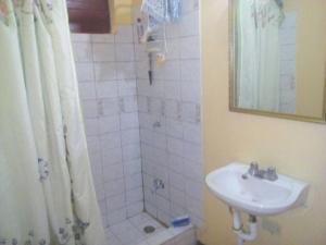 a bathroom with a sink and a shower with a mirror at Leslies' Home in Portmore