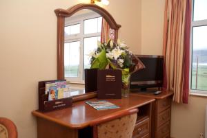 uma secretária com um espelho e um vaso de flores em Achill Cliff House Hotel & Restaurant em Keel