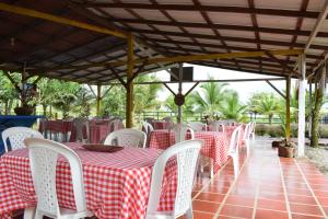 a row of tables and chairs with red and white table cloth at Hotel Nuquimar in Nuquí