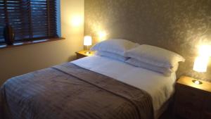 una camera da letto con letto, lenzuola e cuscini bianchi di Countryside Lodge a Peterborough