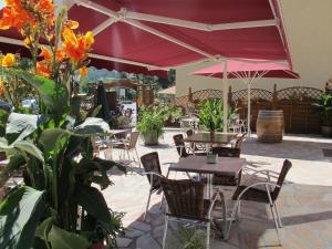 un patio al aire libre con mesas, sillas y flores en Hôtel Bel'Air en Jausiers