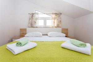 una camera con due letti con lenzuola verdi e una finestra di Apartments Blaža a Podstrana