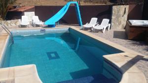 een blauw zwembad met een glijbaan en stoelen bij Casa Ary in Tesejerague