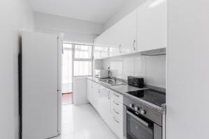 eine weiße Küche mit Herd und Spüle in der Unterkunft The Perfect Porto Apartment in Porto