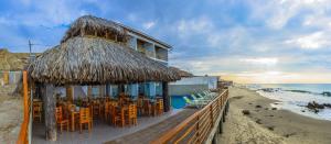 a restaurant with chairs and tables on the beach at Akas Hotel Apartamentos in Canoas De Punta Sal