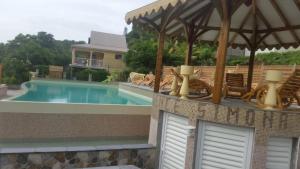 a swimming pool with chairs and an umbrella on a house at Résidence SIMONA in Deshaies +31 photos