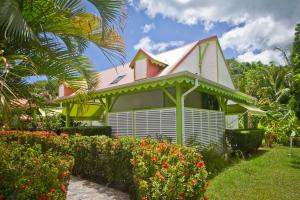 a yellow house with a pink roof and some flowers at Résidence SIMONA in Deshaies