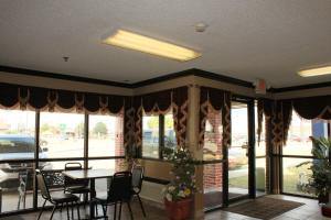 a dining room with a table and chairs and windows at Holiday Lodge in Pittsburg