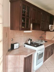 uma cozinha com armários de madeira e um forno de fogão branco em Apartamento con jardin em Cochabamba