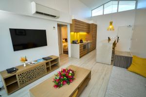منتجع تاومياسينا آيلاند في أبيا: غرفة معيشة فيها تلفزيون وطاولة عليها ورد