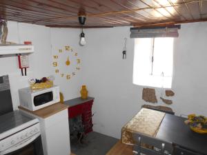a kitchen with a stove and a microwave on the wall at Casa da Avó Teresinha in Sabugueiro