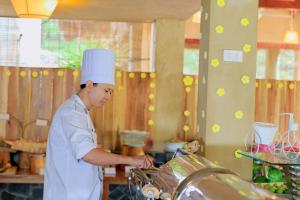 a chef standing in a kitchen preparing food at Daisy Resort in Phú Quốc