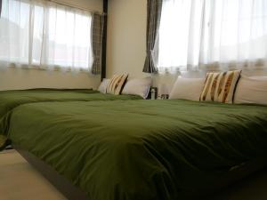 een slaapkamer met een groot groen bed en ramen bij Dining Pension Ezura in Shirahama