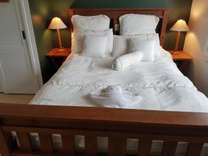 a bedroom with a bed with white sheets and pillows at Fernglen B&B in Auckland