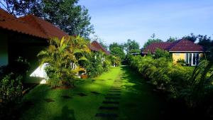 een groene tuin met huizen en palmbomen bij CharPoot Cottage Khao Lak in Khao Lak