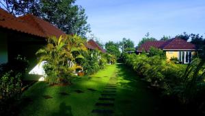 zielony dziedziniec z domami i palmami w obiekcie CharPoot Cottage Khao Lak w mieście Khao Lak